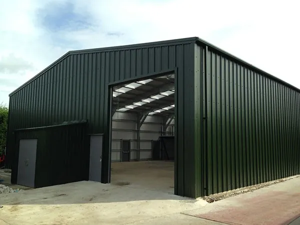 Tall green clad farm building with a large open door